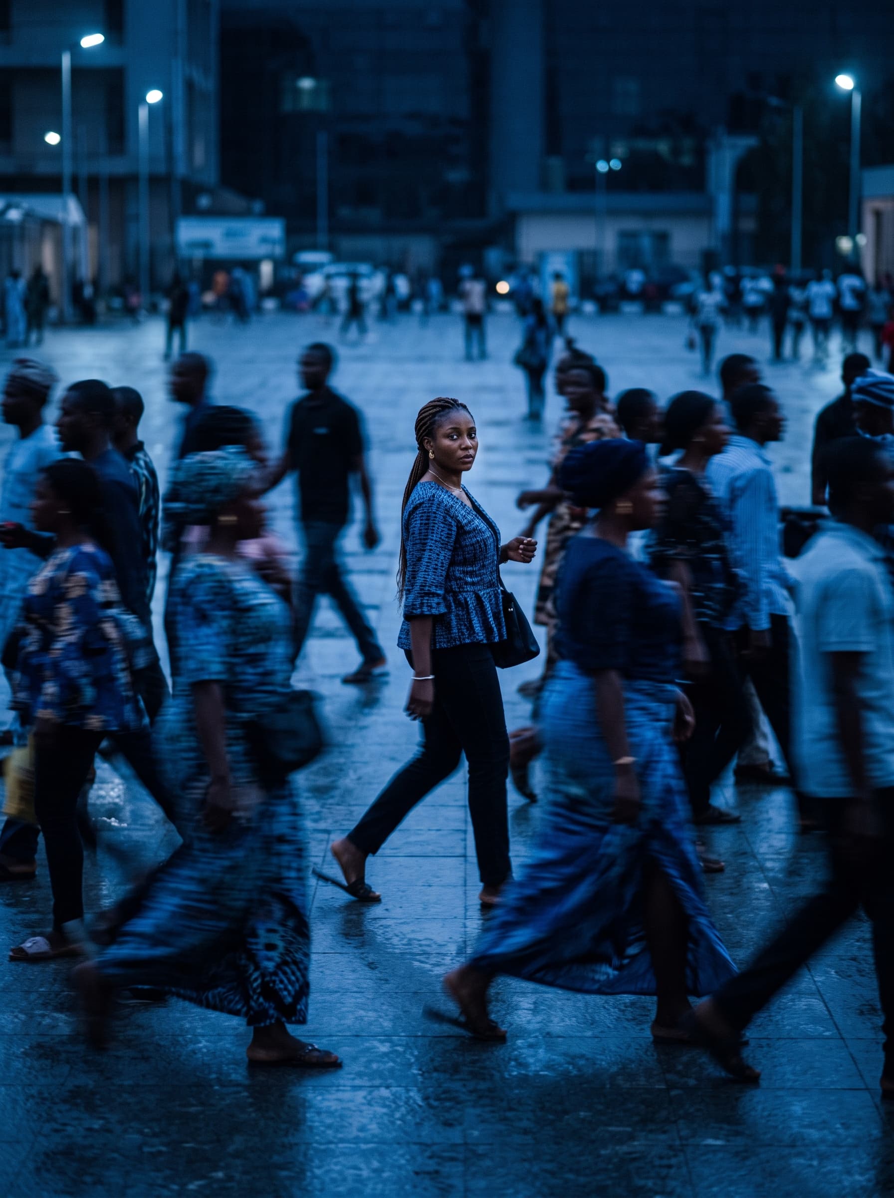 One person in sharp focus amid a motion-blurred crowd crossing a plaza